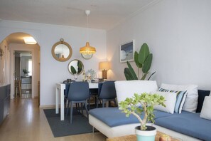 A modern living room with a sofa, dining table, chairs, and a potted plant. - SingularStays El Puig Beach II (El Puig de Santa Maria)