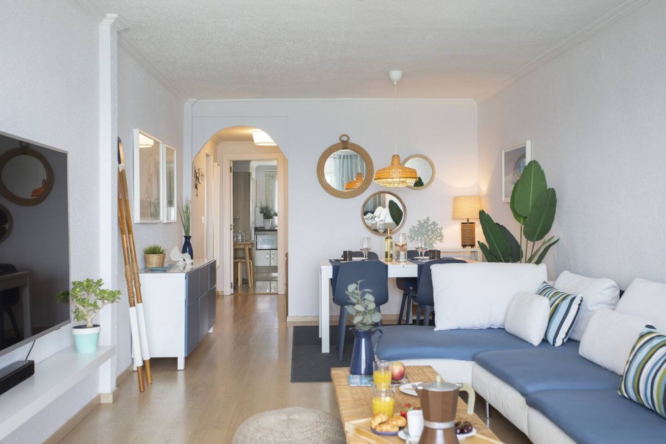 Een moderne woonkamer met een bank, eettafel en keuken op de achtergrond.