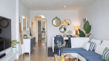 Een moderne woonkamer met een bank, eettafel en keuken op de achtergrond.