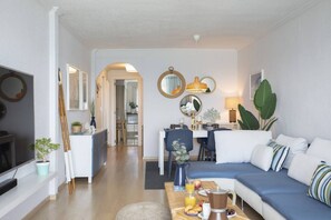 A modern living room with a sofa, dining table, and kitchen in the background. - SingularStays El Puig Beach II (El Puig de Santa Maria)