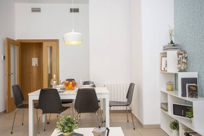 A modern dining area with a white table, black chairs, and a hanging light fixture. - SingularStays Mar44 V (Valencia / València)