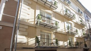 A multi-story building with balconies, some with plants.