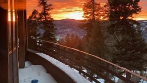 Un balcon offrant une vue sur un coucher de soleil se reflétant sur un paysage boisé.