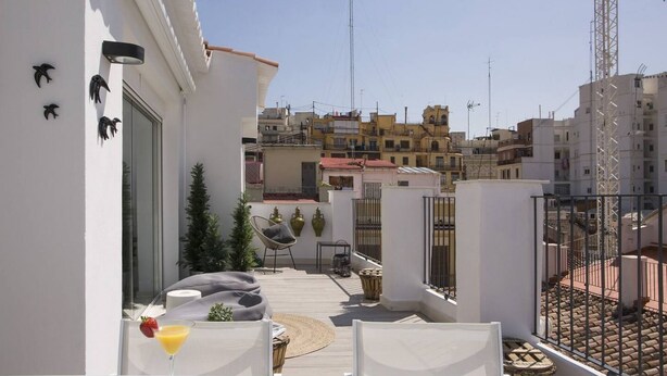 Une terrasse sur le toit avec une table, des chaises et une boisson.