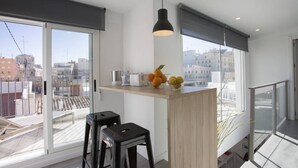 Une cuisine moderne dotée d’une grande fenêtre, d’un îlot central en bois et de deux tabourets de bar noirs.