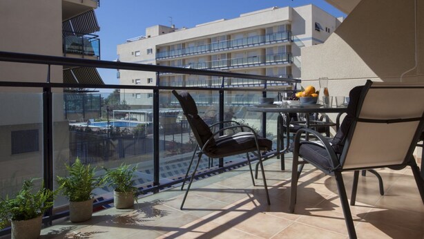 A balcony with a glass railing, a table with chairs, and potted plants. - SingularStays Moncofar Beach (Moncofar)