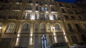 A multi-story building with balconies and arched windows, featuring a central entrance with a door and a sign above it. - SingularStays Parque Central XIV (Valencia)