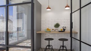 A modern kitchen with a glass door leading to a balcony, two stools, and pendant lighting. - SingularStays Parque Central XIV (Valencia)