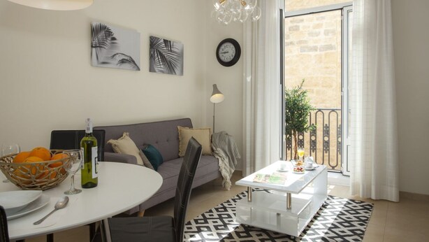 A modern living room with a round dining table, a sofa, a patterned rug, and a balcony with a view. - SingularStays Seu I (València)