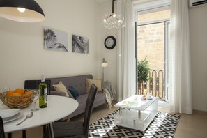 A modern living room with a round dining table, a sofa, a patterned rug, and a balcony with a view. - SingularStays Seu I (València)