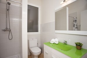 A bathroom with a shower, toilet, sink, and a mirror. - SingularStays Seu I (València)