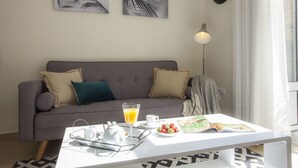 A living room with a grey sofa, a white coffee table, and a breakfast setup including a teapot, glasses, and a plate of strawberries. - SingularStays Seu I (València)