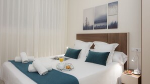 A neatly made bed with a teal bedspread, white pillows, and a tray with breakfast items. - SingularStays Seu I (València)