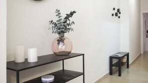 A hallway with a black console table holding a vase with green foliage, two white candles, and a small round clock. - SingularStays Seu I (València)