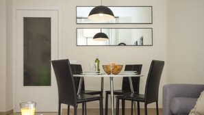 A modern dining area with a table set for four, black chairs, a glass coffee table, and a grey sofa. - SingularStays Seu I (València)