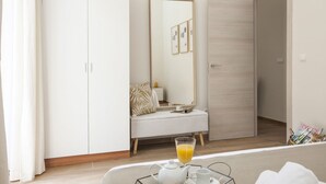 A bedroom with a wardrobe, a bedside table with a glass of orange juice, a mirror, and a door leading to another room. - SingularStays Seu VI (València)