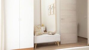 A minimalist room with a white bench, a large mirror, and a wooden door. - SingularStays Seu VI (València)