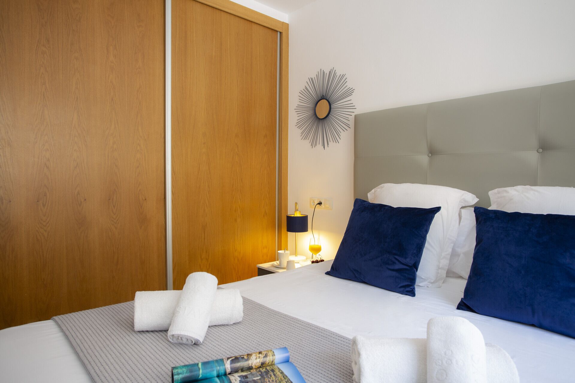 Une chambre d’hôtel avec un lit, une table de chevet, une horloge murale et une armoire en bois.