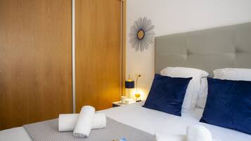 Une chambre d’hôtel avec un lit, une table de chevet, une horloge murale et une armoire en bois.
