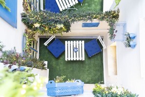 A rooftop terrace with a small seating area, a blue planter, and decorative greenery.