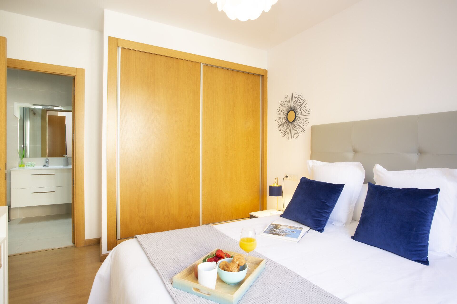 Una habitación de hotel con cama, mesita de noche y armario de madera.