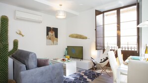 A living room with a grey sofa, a cactus, a TV, and a dining area with a table and chairs. - SingularStays Valencia Center III (València)