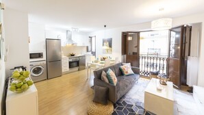 Eine moderne Wohnung mit Küche, Essbereich und Wohnzimmer. Sie umfasst ein Sofa, einen Couchtisch und einen Esstisch.