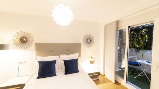 Ein Schlafzimmer mit einem großen Bett, zwei Wandleuchten und einer Deckenlampe.