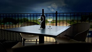 A table with a bottle and two glasses on a balcony overlooking a beach. - Water's Edge Suite 201 - Beautiful, Spacious & Luxurious (Garden City)