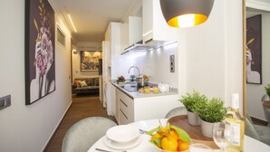 A modern kitchen with a dining area, featuring a central island, white cabinetry, and a hanging light fixture.
