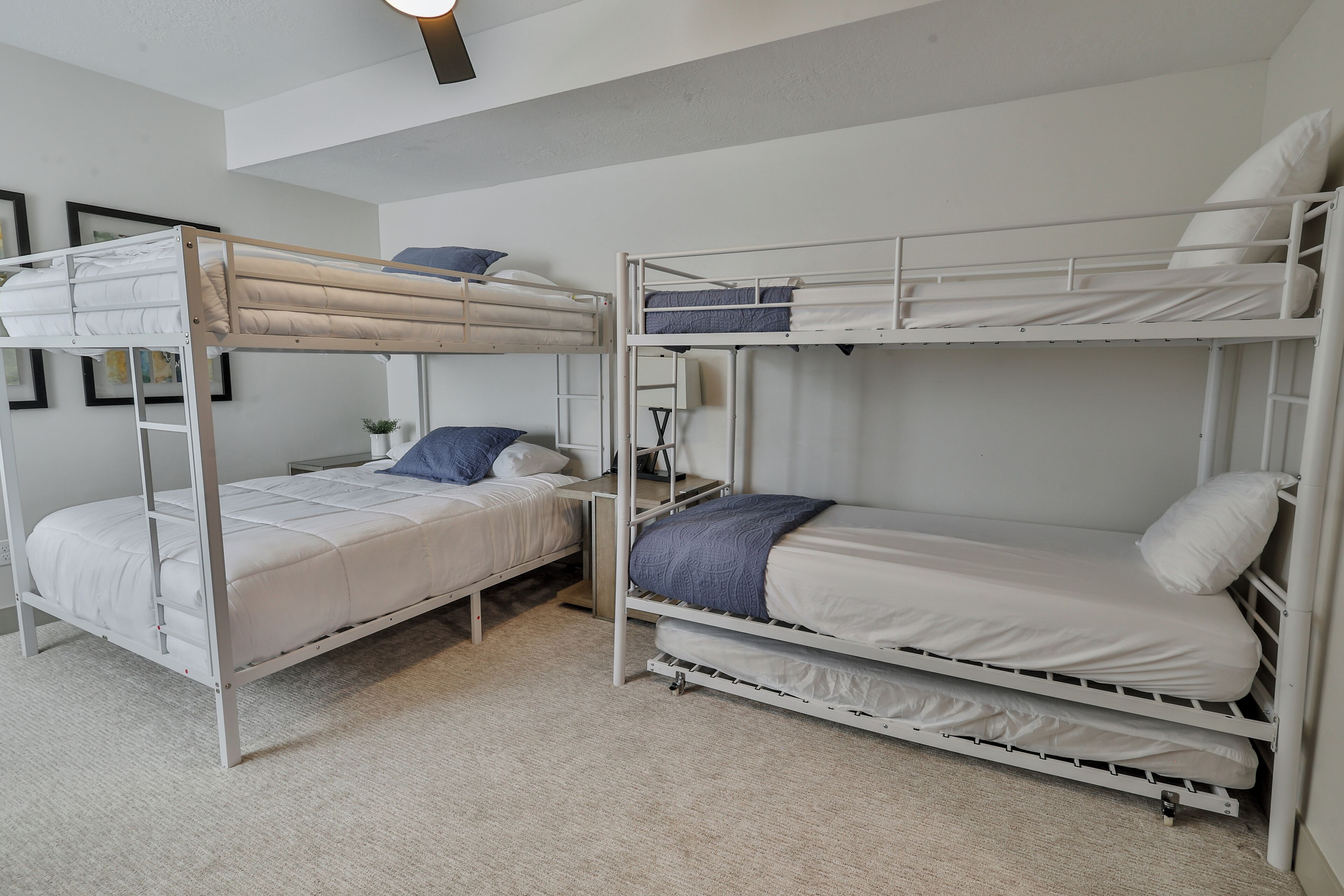 A bunk bed room with a desk and chair, a small plant, and a framed picture on the wall.