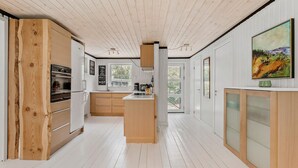 Eine moderne Küche mit Holzschnitzereien, einer zentralen Kochinsel und einem großen Fenster, das für natürliches Licht sorgt.