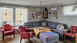 A cozy living room with a grey sofa, red armchairs, a wooden coffee table, and a grey ottoman. - 3 bedroom cozy home in Snefjord (Snefjord)