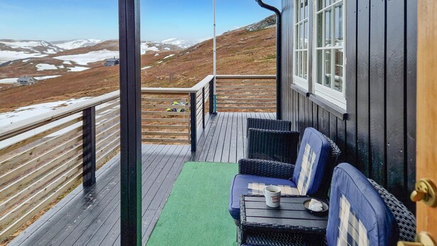 A wooden deck with a sofa and a table, overlooking a snowy landscape. - 3 bedroom cozy home in Snefjord (Snefjord)