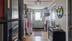 A narrow hallway leading to a kitchen with a window, wooden floors, and a rug. - 3 bedroom cozy home in Snefjord (Snefjord)