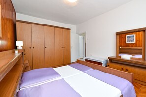 Ein Schlafzimmer mit einem Bett, einem Holzschrank, einem Nachttisch und einem Spiegel.