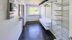 A narrow hallway with a black tiled floor, a window with a view of greenery, and a wall-mounted drying rack. - 3 bedroom beautiful home in Gislaved (Gislaved)