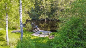 A serene outdoor area with a wooden deck, a small bridge, and a pond surrounded by lush greenery. - 3 bedroom beautiful home in Gislaved (Gislaved)