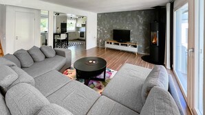 A modern living room with a grey sectional sofa, a round black coffee table, a flat-screen TV, and a fireplace. - 3 bedroom beautiful home in Gislaved (Gislaved)