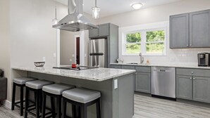 Una cocina moderna con armarios grises, electrodomésticos de acero inoxidable y una isla grande con taburetes de bar.