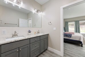 A modern bathroom with a large mirror, double sink vanity, and a walk-in closet.