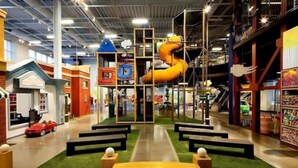 Ein Indoor-Spielbereich mit Rutsche, Spielgeräten und Sitzbereichen.