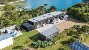 A modern house with a large deck, a hot tub, and a view of the sea.