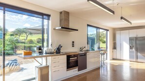 A modern kitchen with large windows, a built-in oven, and a stainless steel refrigerator.