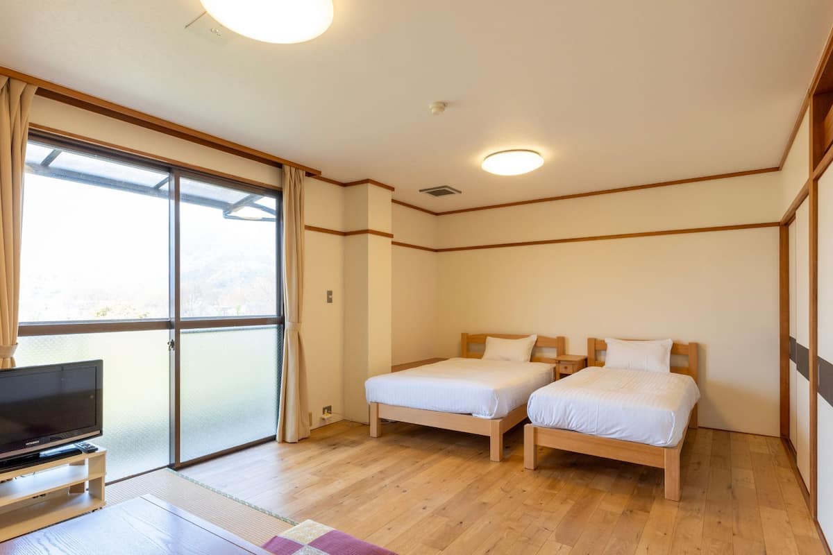 Habitación de hotel con dos camas, televisión y un amplio ventanal corredero.