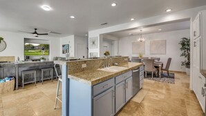 A modern kitchen with a granite countertop, built-in cabinets, and a dining area with a table and chairs.