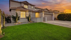 A modern two-story house with a well-maintained lawn, a garage, and a driveway.