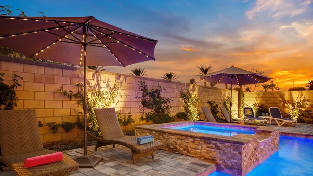A poolside area with lounge chairs, umbrellas, and a brick wall.