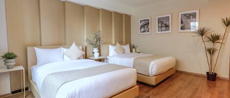 A modern hotel room with two beds, wooden flooring, a large window, and a potted plant.