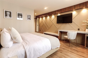 Una camera d'hotel moderna con un letto grande, una scrivania e una televisione a schermo piatto fissata al muro.